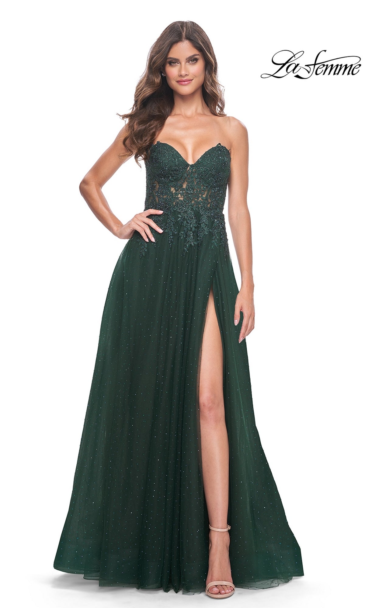 A woman in the La Femme Sheer-Lace Long Beaded Prom Dress 32253—strapless, dark green, with a sweetheart neckline, lace bodice, high slit, and sparkly details—stands against a white background.